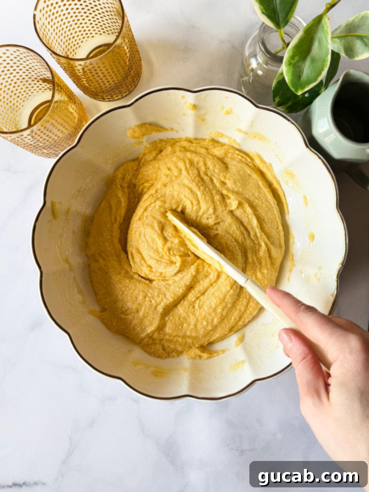 Hand stirring gluten-free cornbread batter in a bowl.