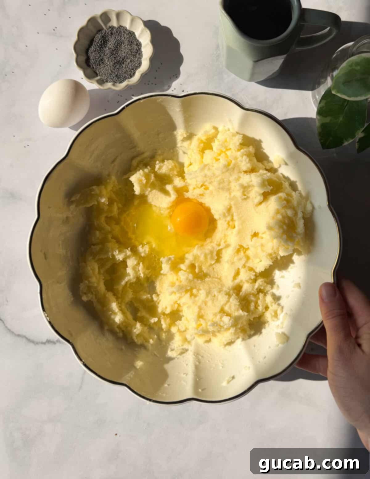 Lemon Poppyseed Bliss: A Gluten-Free Delight 6 A bowl of creamed butter and sugar with a cracked egg on top, about to be mixed in.
