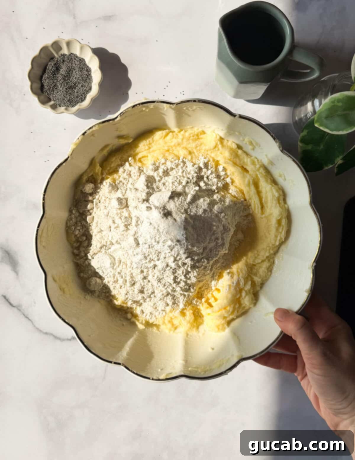 Lemon Poppyseed Bliss: A Gluten-Free Delight 10 A bowl of creamed butter, sugar, and eggs with gluten-free flour on top, ready to be mixed in.