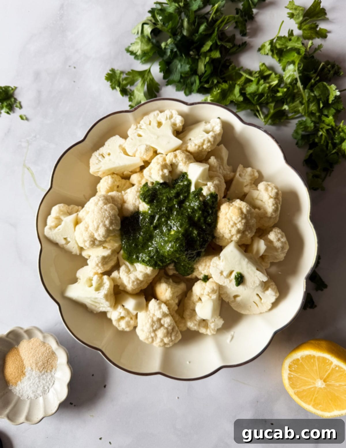 Herb-Crusted Roasted Cauliflower 6 Cauliflower florets in a bowl with herb oil being poured on top.