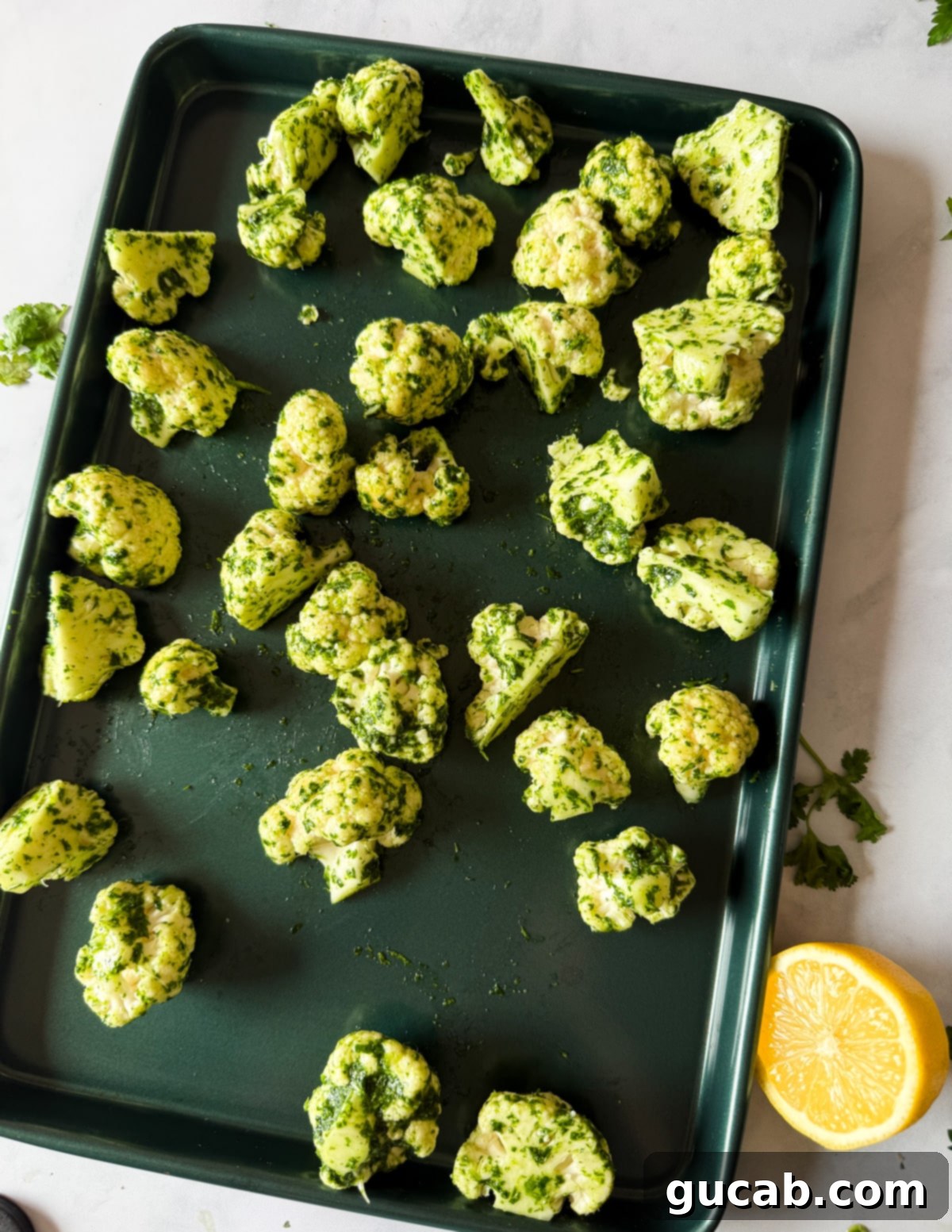 Herb-Crusted Roasted Cauliflower 8 Herb oil coated cauliflower florets spread out on a sheet pan before roasting.
